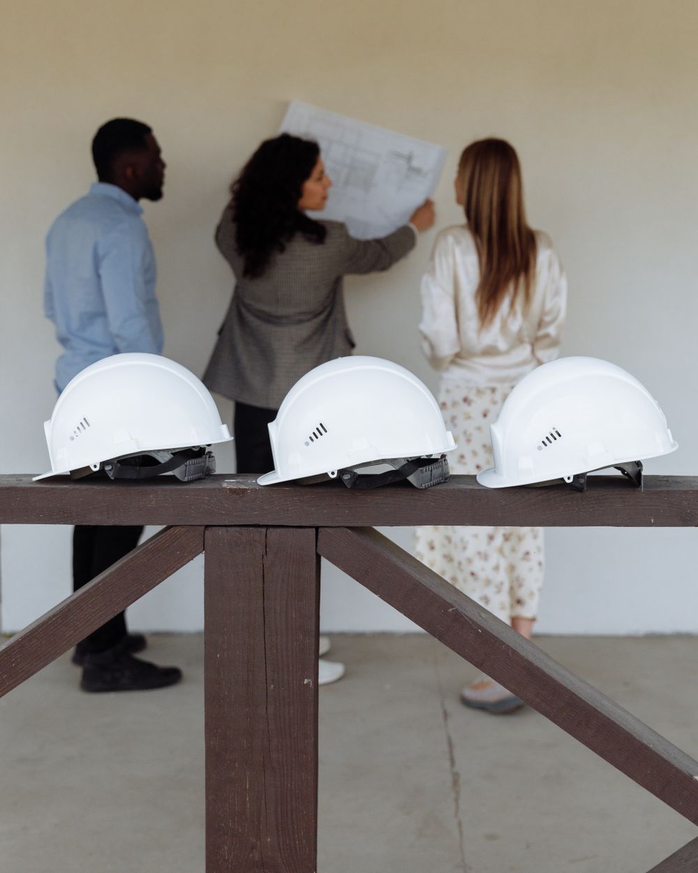 A developer's team reviewing a building plan, hard hats on the rail in front of them